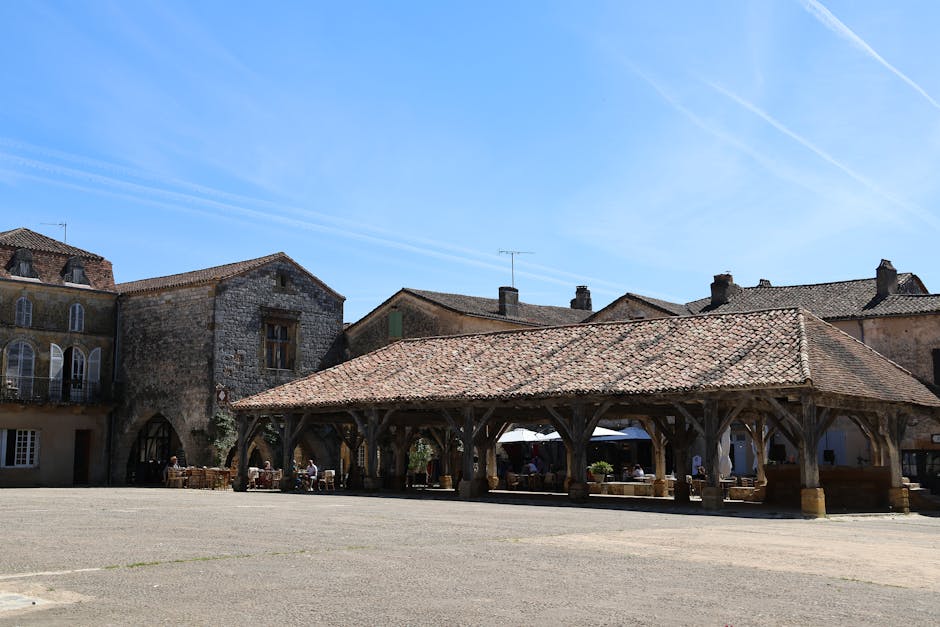 Place de village français avec architecture traditionnelle sous un ciel bleu